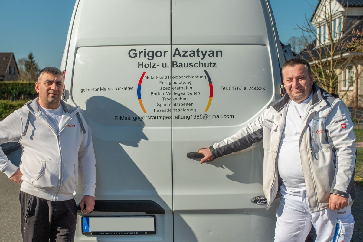 Arbeiter stehen vor Firmenwagen mit Firmenaufschrift