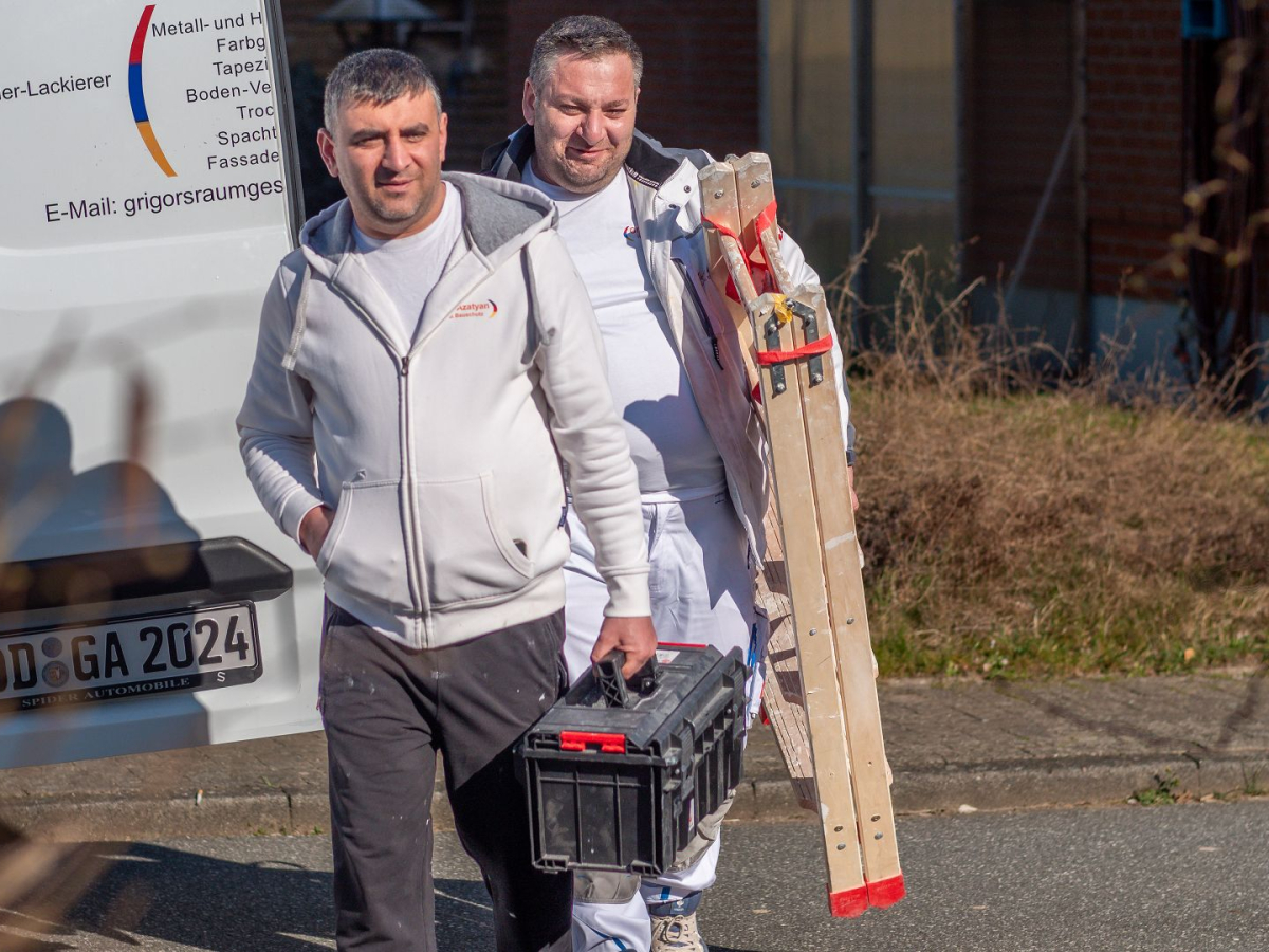 Arbeiter mit Leitern auf dem Weg zur Baustelle